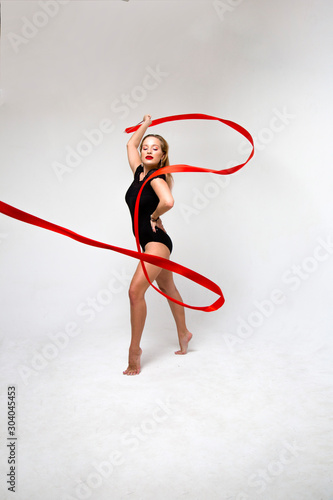 flexible gymnast with red ribbon on a white background in a jump