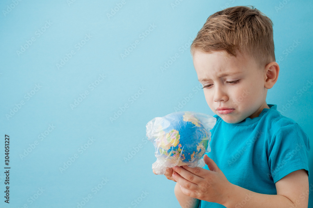 Little boy with a globe in a package on a blue background Little boy with a globe in a package on a blue background