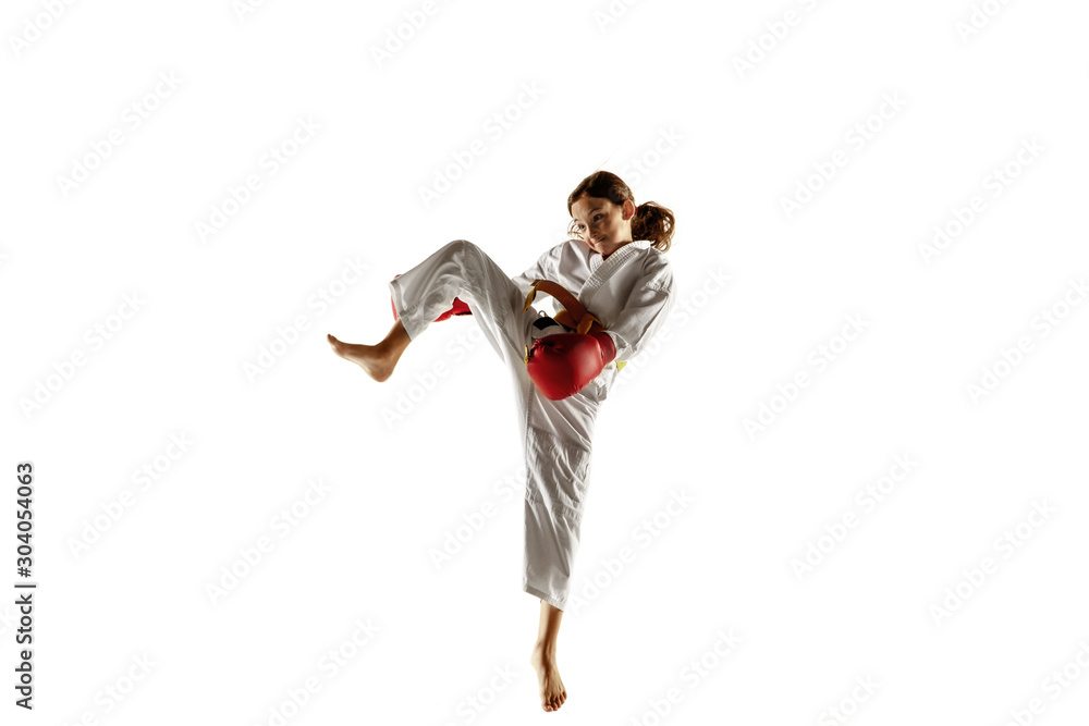 Confident junior in kimono practicing hand-to-hand combat, martial arts. Young female fighter with yellow belt s training on white studio background. Concept of healthy lifestyle, sport, action.