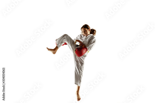 Confident junior in kimono practicing hand-to-hand combat, martial arts. Young female fighter with yellow belt s training on white studio background. Concept of healthy lifestyle, sport, action.