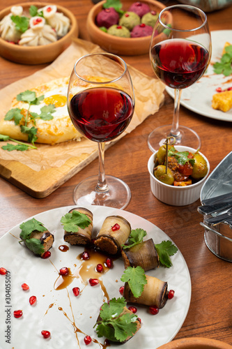 Traditional georgian snack pkhali rolled into eggplant slices on the table with other georgian food and wine