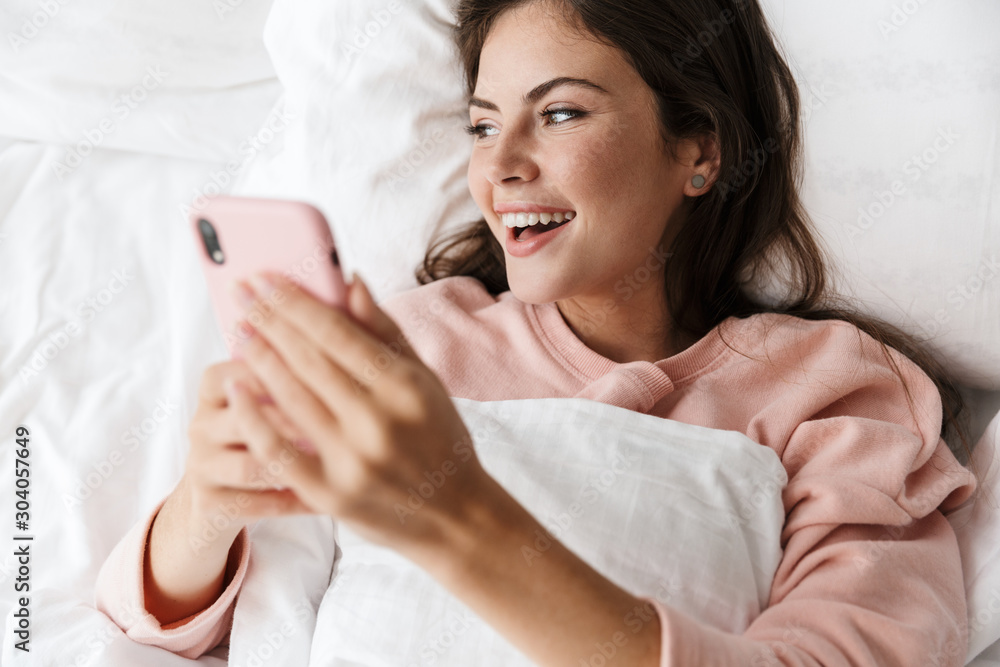 Cheerful lovely young girl wearing pajamas laying in bed Cheerful lovely young girl wearing pajamas laying in bed
