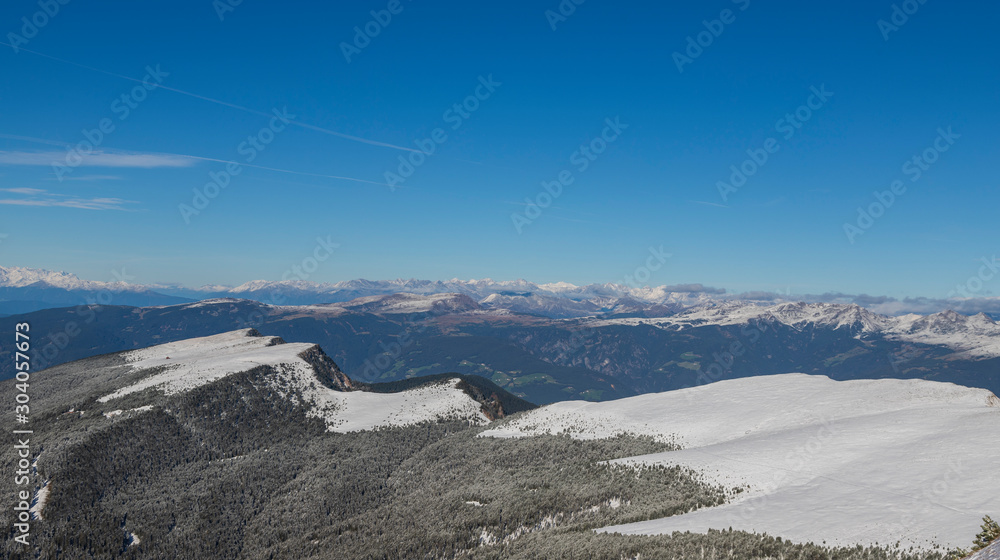 Seceda in the Italian Dolomites under snow. The background is a blue sky with clouds