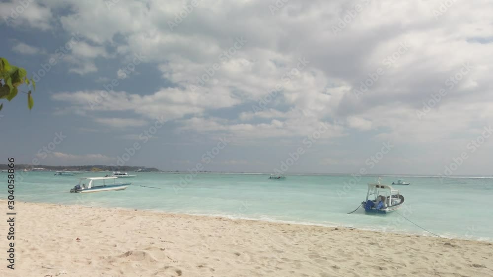 Beautiful Nusa Lembongan, Bali Indonesia beach with blue ocean, white sand, traditional fishing boats and great weather. Peoples surfing and swimming. Beautiful Nusa Lembongan, Bali Indonesia beach with blue ocean, white sand, traditional fishing boats and great weather. Peoples surfing and swimming.