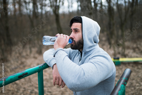 Sportive man drinks water after the training 