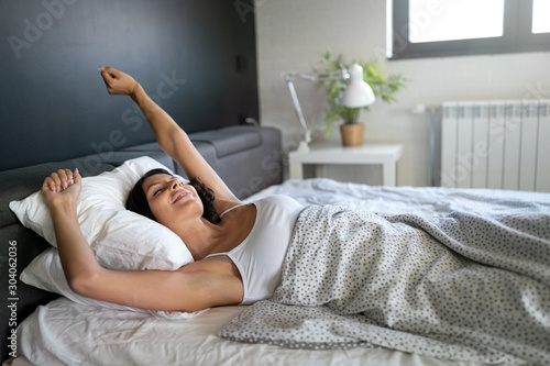Woman stretching in bed after wake up, entering a day happy and relaxed