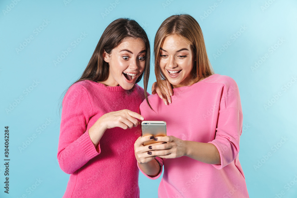 Photo of surprised young women using and pointing finger at cellphone Photo of surprised young women using and pointing finger at cellphone