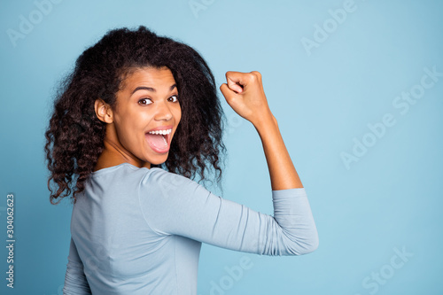 Side profile photo of cheerful excited cute nice pretty girlish feminine youngster demonstrating strength in her muscles after years of training isolated blue pastel color background