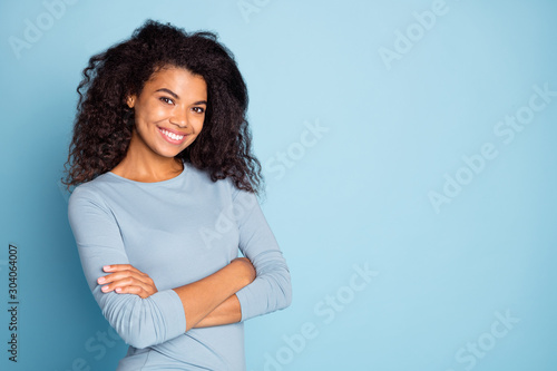 Photo of cheerful cute nice pretty charming youngster with arms crossed smiling toothily near empty space brown haired isolated pastel blue color background