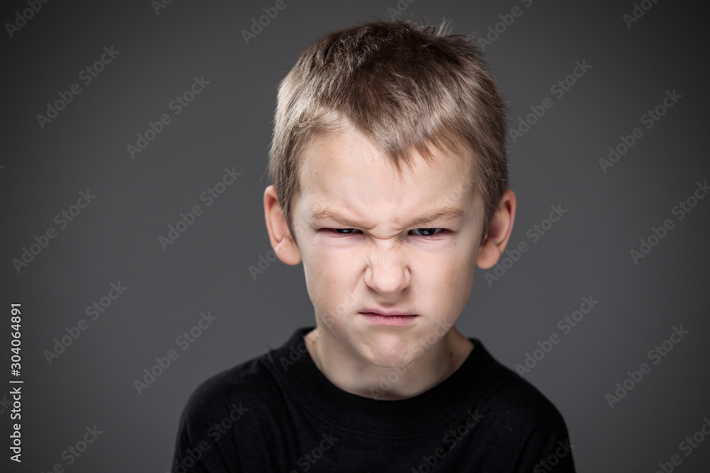 Fototapeta premium Loads of aggression in a little boy - education concept hinting behavioral problems in young children (shallow DOF) - little boy with hands clenched into fists about to punch someone