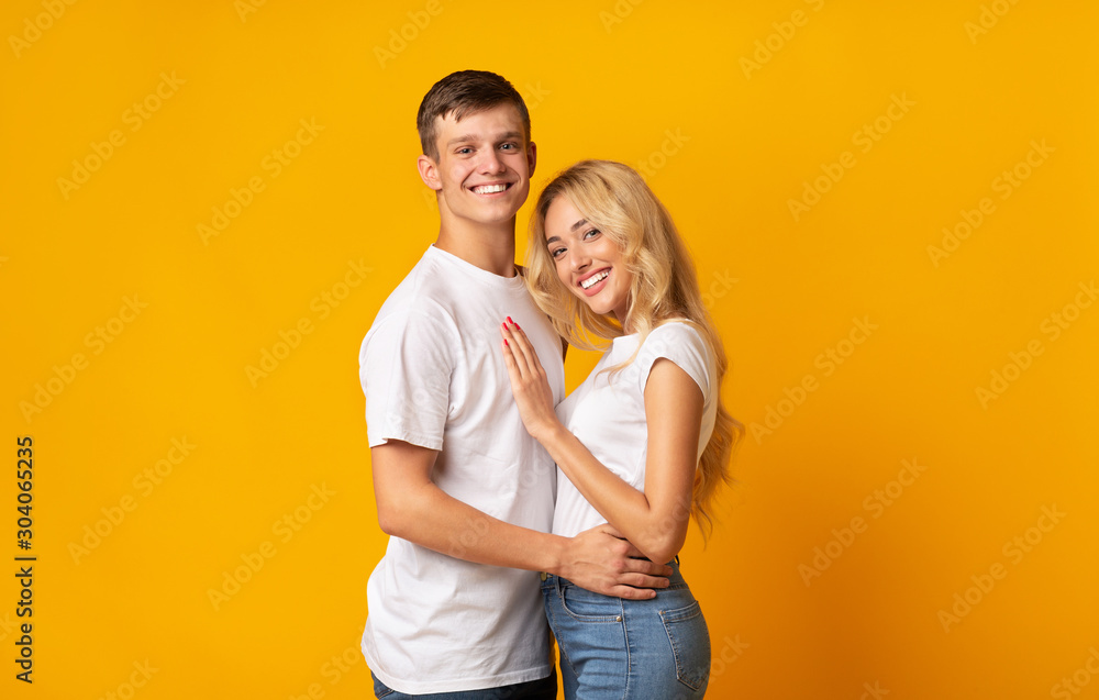 Portrait of young romantic couple cuddling on yellow background Portrait of young romantic couple cuddling on yellow background