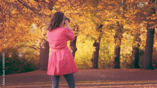 Young fashionable woman taking picturas on her camera in park. photo