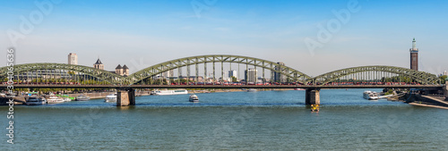 Panorama of the Hohenzollern bridge over Rhine river on a sunny day. Beautiful cityscape of Cologne, Germany with cathedral and Great St. Martin Church in the background