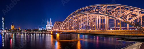 Night panorama of the illuminated Hohenzollern bridge over Rhine river. Beautiful cityscape of Cologne, Germany  with cathedral and Great St. Martin Church in the background © elroce