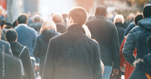 Commuters walking to work with morning sun light in business district, footage of blurred people commuting in downtown from back, busy city life, 4K video