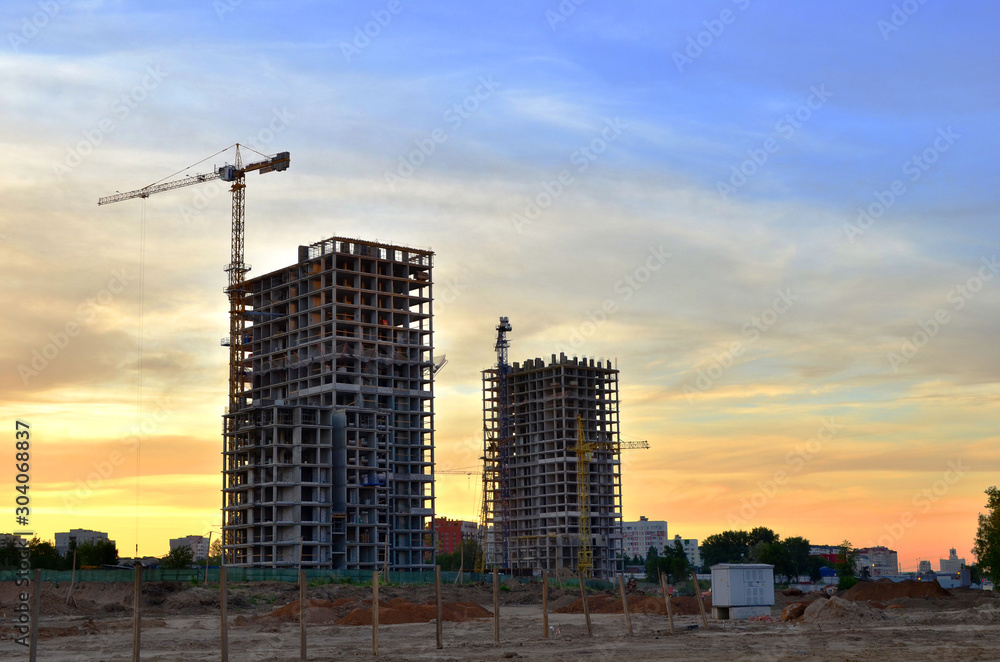 Jib construction tower crane and new residential buildings at a construction site on the sunset and blue sky background - Image