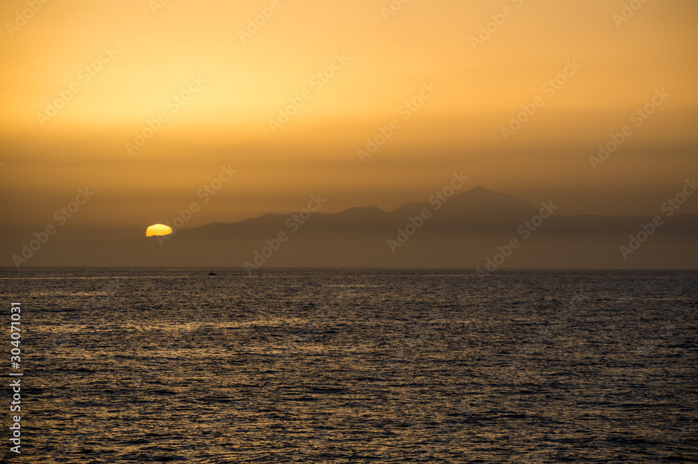 A view of the Island of Tenerife at sundown with the ocean before it. 