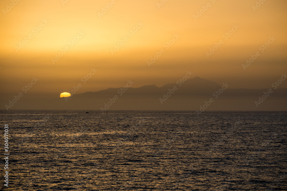 A view of the Island of Tenerife at sundown with the ocean before it. A view of the Island of Tenerife at sundown with the ocean before it.
