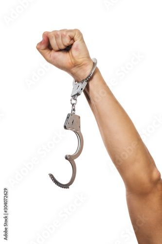 Concept on the theme of freedom. Male handcuffed hand raised up isolated on white background photo