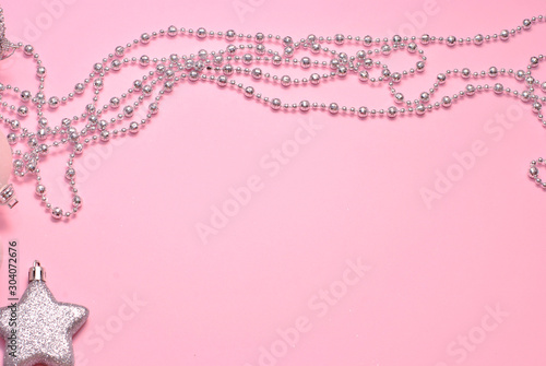 Shiny silver Christmas decoration beads and star on the pink paper background closeup top view macro. Sparkling beautiful background with free copy space place for text
