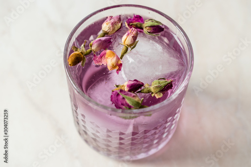 Pink Gin Tonic Cocktail with Dried Rose Buds and Ice in Glass Cup
