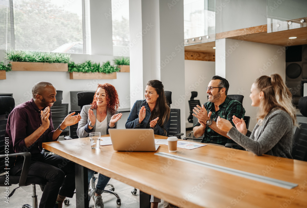 Diverse business team clapping hands and smiling during boardroom meeting Diverse business team clapping hands and smiling during boardroom meeting