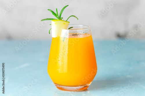 Yellow orange cocktail with melon and mint in glass on blue concrete background, close up