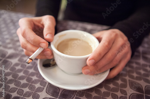 Cup of coffee and a cigarette in the hands of a woman in a cafe