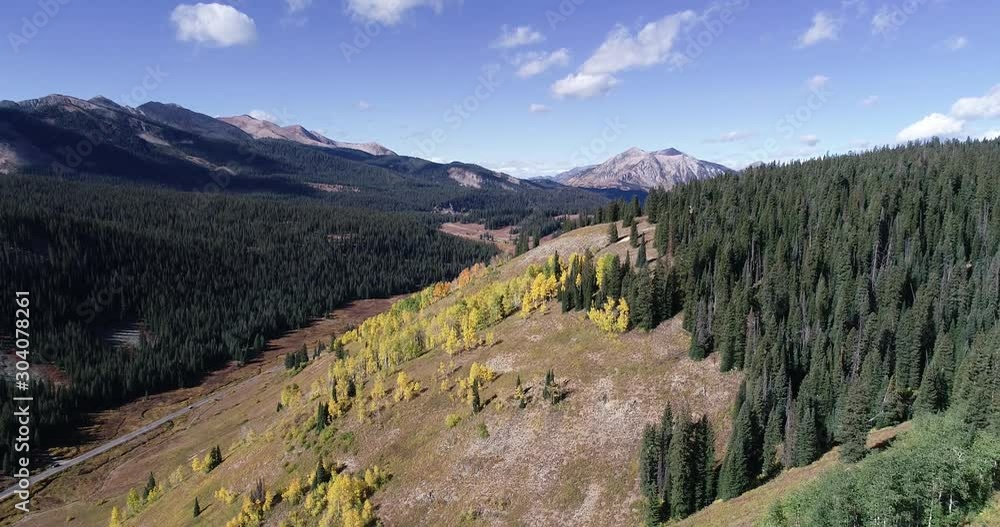 Stark pines and jagged peaks contrast the soft golden aspen leaves as the reveal their fall colors in this 4k drone shot. 60fps. Stark pines and jagged peaks contrast the soft golden aspen leaves as the reveal their fall colors in this 4k drone shot. 60fps.