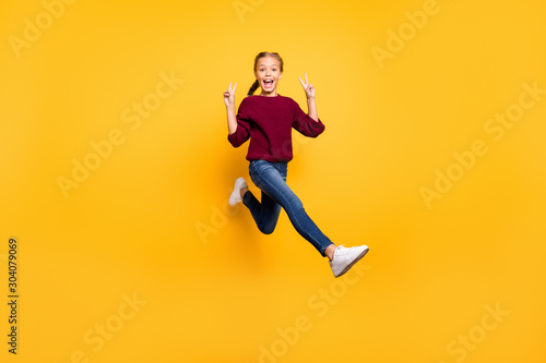 Full length body size view of her she nice attractive cheerful cheery playful pre-teen girl having fun jumping showing double v-sign isolated on bright vivid shine vibrant yellow color background