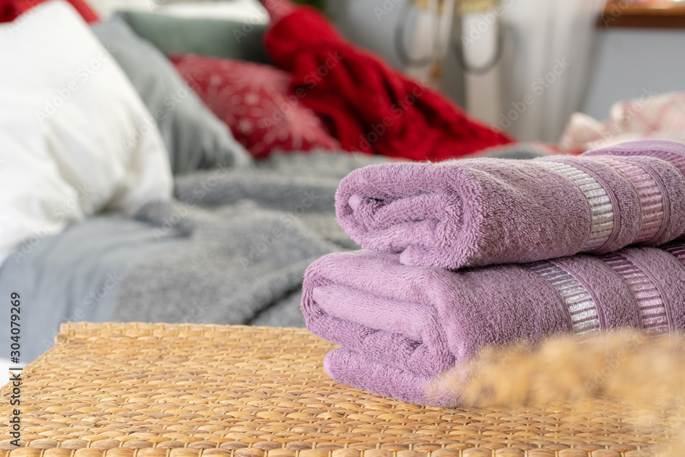 Stack of clean towels on wooden table in bedroom