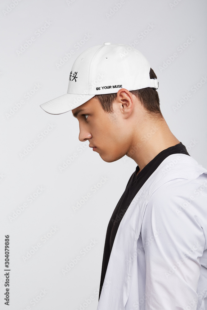 Cropped side photo of a dark-haired man, wearing white baseball cap with Chinese characters print and lettering 