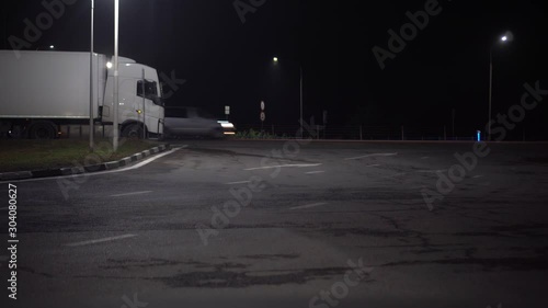 A parked truck on the side of the road under a streetlight. Heavy traffic on the highway in the background. Night time. Ultra HD stock footage