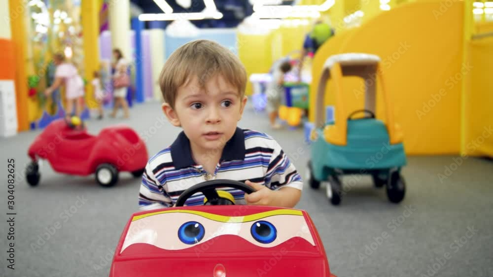 4k handheld video of little boy riding in pedal children car at amusement park in shopping center 4k handheld video of little boy riding in pedal children car at amusement park in shopping center
