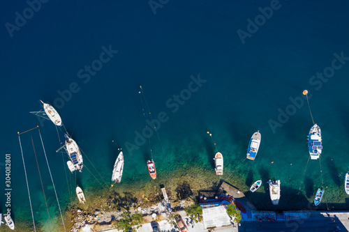 Aerial drone top view photo of colourful wooden traditional fishing boat in turquoise sea shore of Simy island, Greece photo