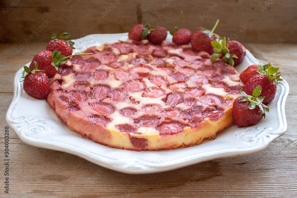 Round strawberry pie with fresh strawberries on white plate dish on wooden table background Round strawberry pie with fresh strawberries on white plate dish on wooden table background