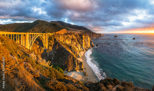 Scenic panoramic view of historic Bixby Creek Bridge along world famous Highway 1 in beautiful golden evening light at sunset with dramatic cloudscape in summer, Monterey County, California, USA photo