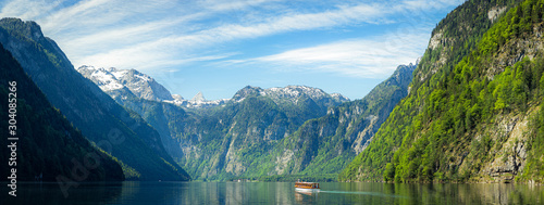 Classic panoramic view of traditional tourist boat on famous Lake Konigssee on a beautiful sunny day with blue sky and clouds in summer, Berchtesgadener Land, Bavaria, Germany
