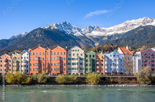 Panoramic view of famous colourful houses and snow-capped alpine mountain tops in the background in the historic city center of scenic Innsbruck on a beautiful sunny day with blue sky, Tyrol, Austria