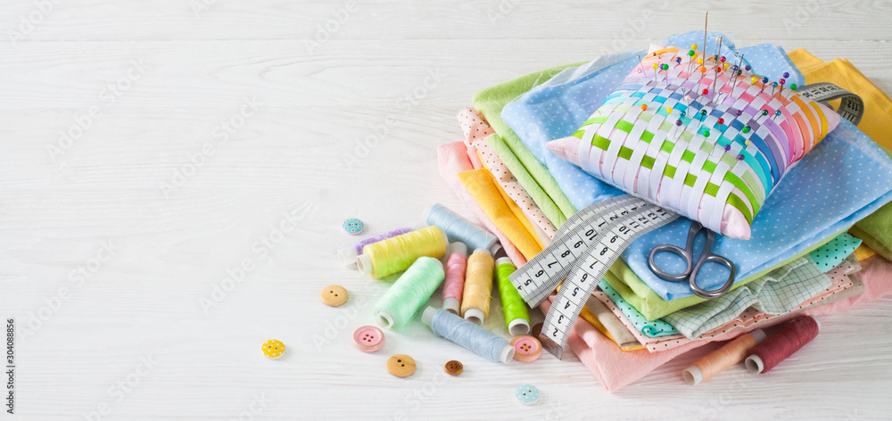 Fototapeta premium Needle box, threads and cotton fabrics for sewing. White background.