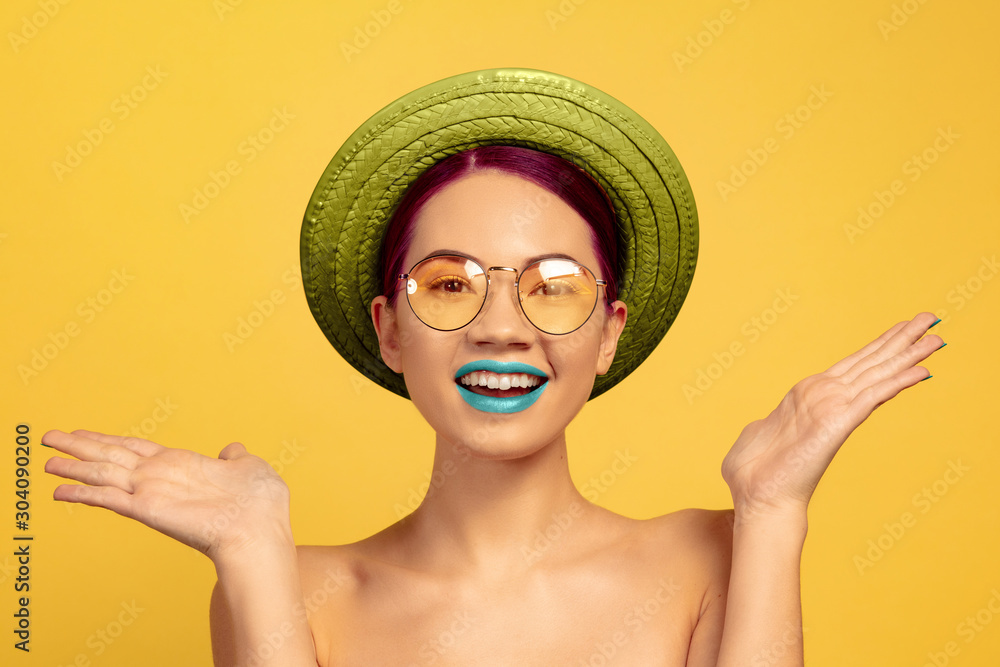 Portrait of beautiful woman with bright make-up, hat and sunglasses on yellow studio background. Stylish and fashionable make and hairstyle. Colors of summer. Beauty, fashion and ad concept. Surprised Portrait of beautiful woman with bright make-up, hat and sunglasses on yellow studio background. Stylish and fashionable make and hairstyle. Colors of summer. Beauty, fashion and ad concept. Surprised