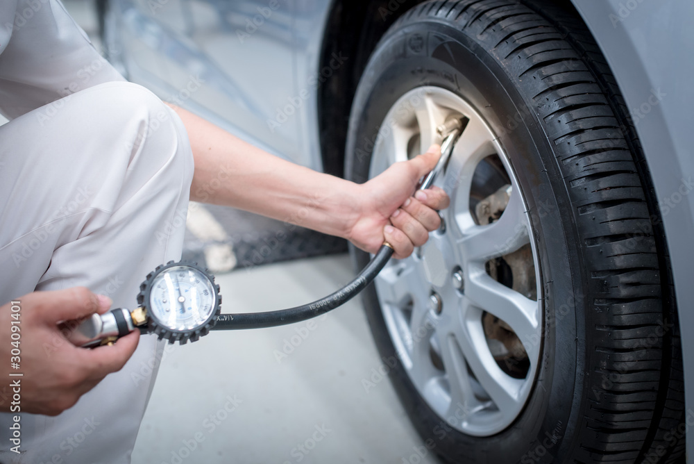 Close-Up Of Hand holding pressure gauge for car tyre pressure measurement