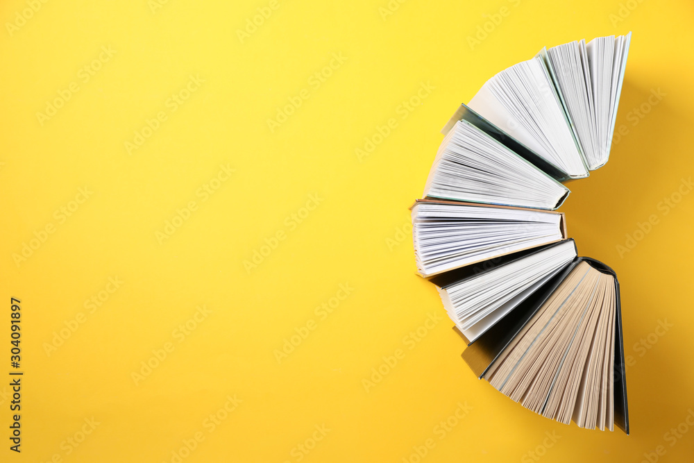 Books on yellow background, top view and space for text