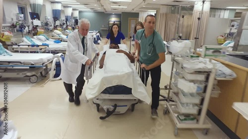 A sick patient being rushed on a gurney by a doctor and nurses through the hospital halls.