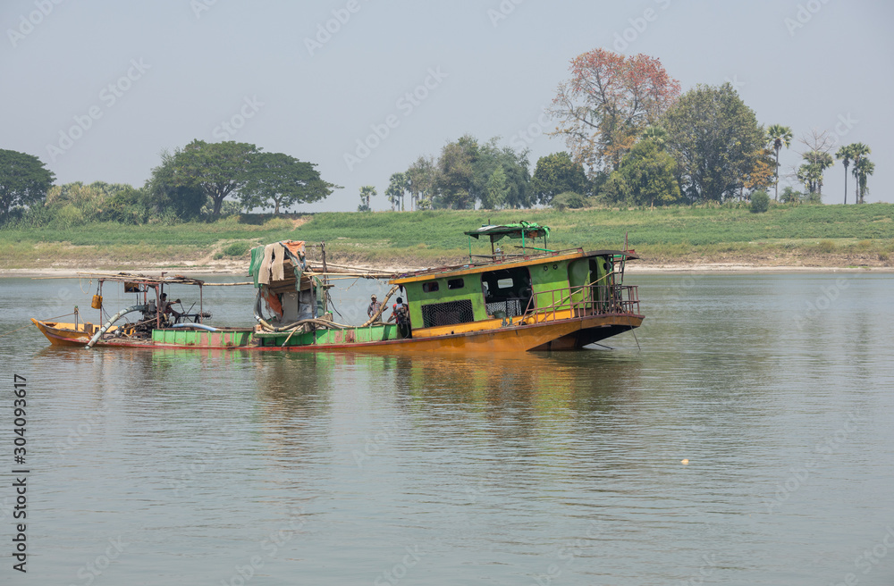 Floating dredge for the extraction of gold and precious stones, Irrawaddy river, Burma. Copy space for text.