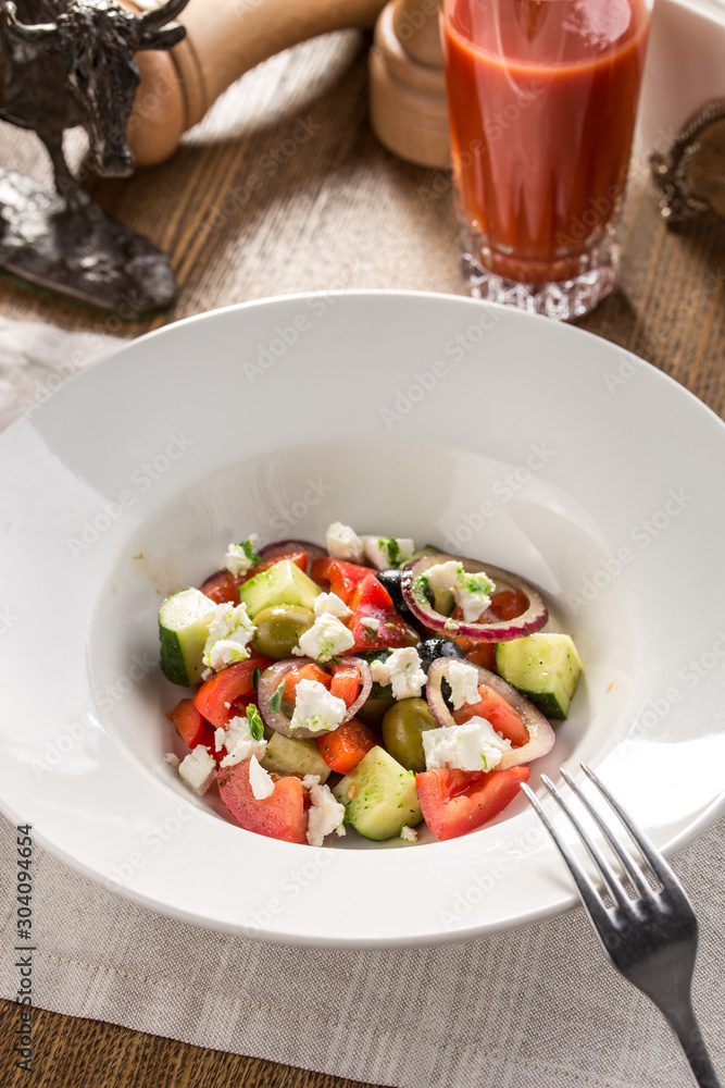 Fresh Greek salad in bowl with olives tomato feta cheese cucumber and onion on textile napkin Fresh Greek salad in bowl with olives tomato feta cheese cucumber and onion on textile napkin