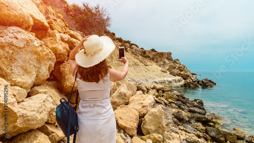 woman photographing an idyllic seascape with the beach and mountains in Turkey