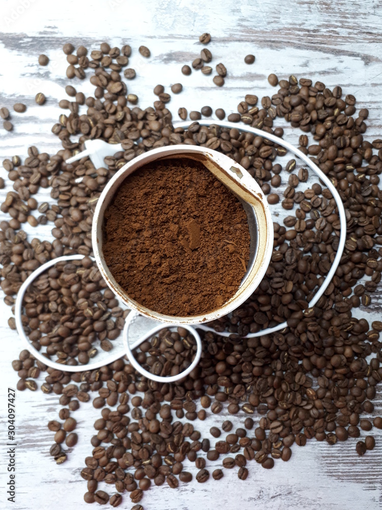 close-up of a coffee grinder with ground coffee on a wooden tabletop background with freshly roasted brown aromatic coffee beans close-up of a coffee grinder with ground coffee on a wooden tabletop background with freshly roasted brown aromatic coffee beans