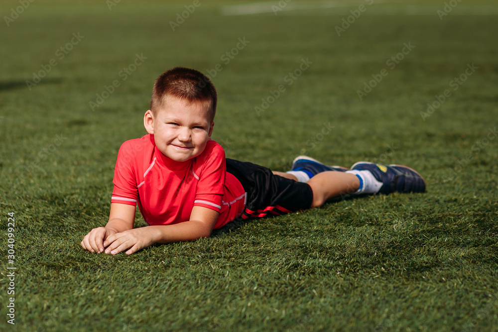 Boy in red T-shirt lies on green grass Boy in red T-shirt lies on green grass