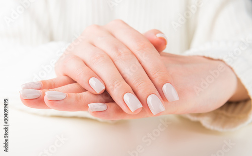 female hand with beige nail design..